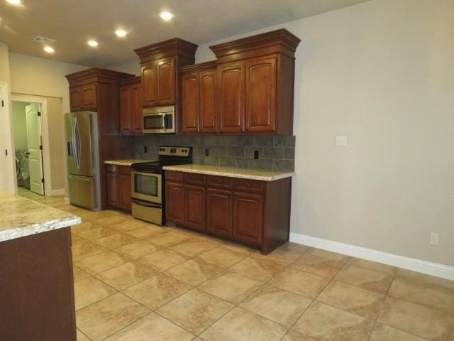 kitchen featuring backsplash, light tile patterned flooring, and appliances with stainless steel finishes