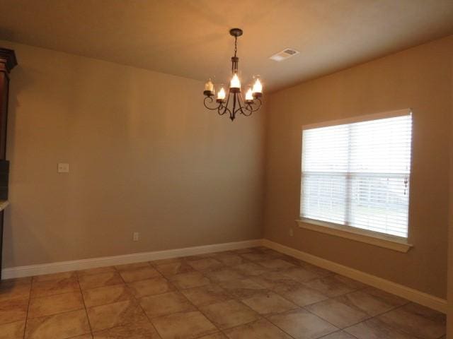 tiled spare room featuring a chandelier