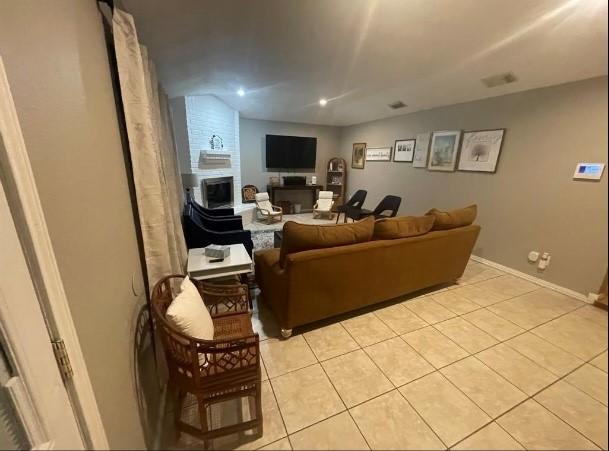 living room featuring a fireplace, vaulted ceiling, and light tile patterned flooring