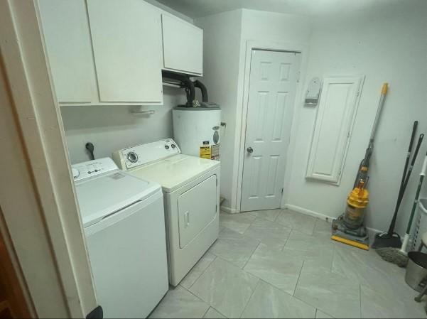 laundry area featuring washing machine and clothes dryer, cabinets, and gas water heater