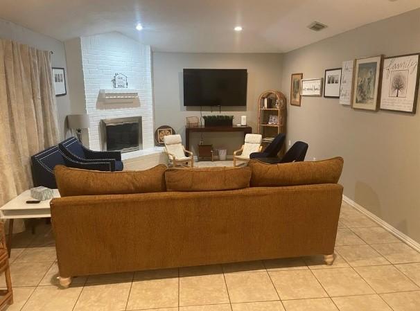 tiled living room featuring a brick fireplace