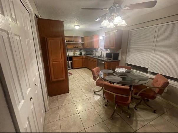 kitchen featuring appliances with stainless steel finishes, a textured ceiling, ceiling fan, sink, and light tile patterned floors