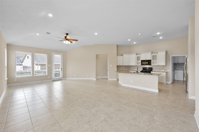 kitchen with light stone counters, ceiling fan, black appliances, white cabinets, and washer / dryer