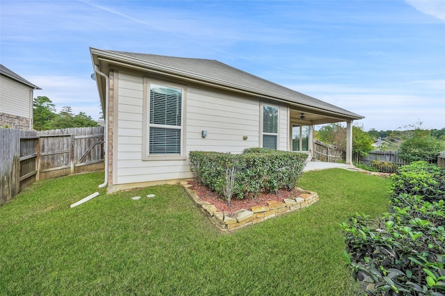 rear view of property featuring ceiling fan and a yard