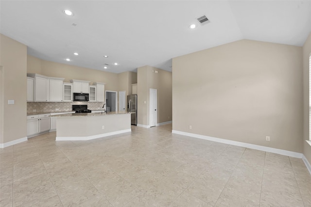 kitchen with black appliances, white cabinets, a center island with sink, sink, and vaulted ceiling