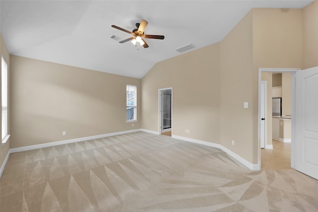 empty room featuring light colored carpet, vaulted ceiling, and ceiling fan