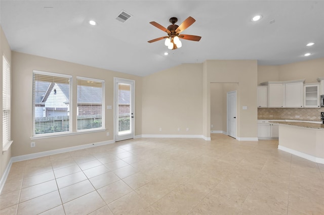 unfurnished living room with ceiling fan, light tile patterned flooring, and vaulted ceiling