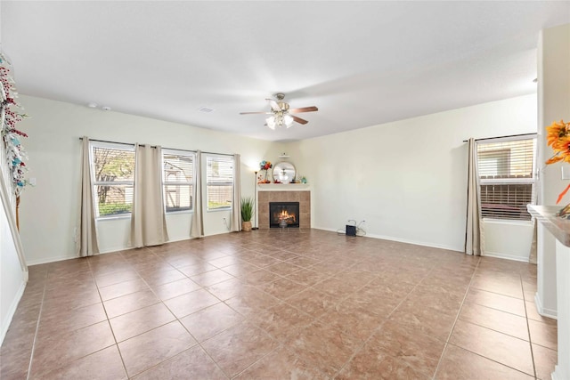 unfurnished living room with ceiling fan, light tile patterned floors, and a tile fireplace