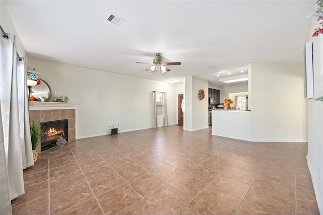 unfurnished living room featuring ceiling fan, a fireplace, and light tile patterned floors