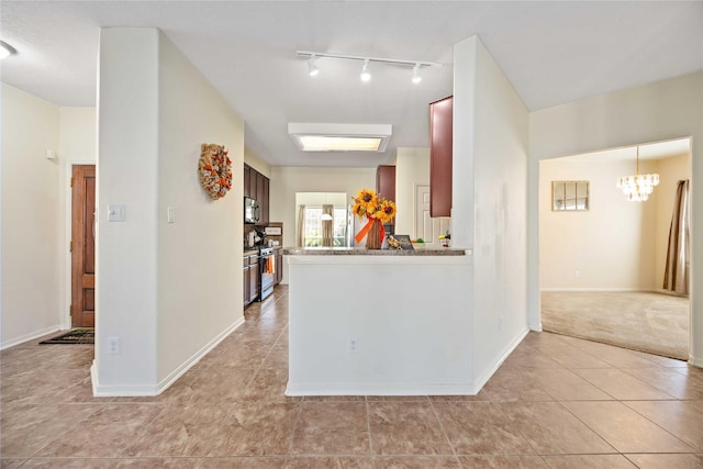 kitchen featuring light carpet, appliances with stainless steel finishes, rail lighting, kitchen peninsula, and a notable chandelier