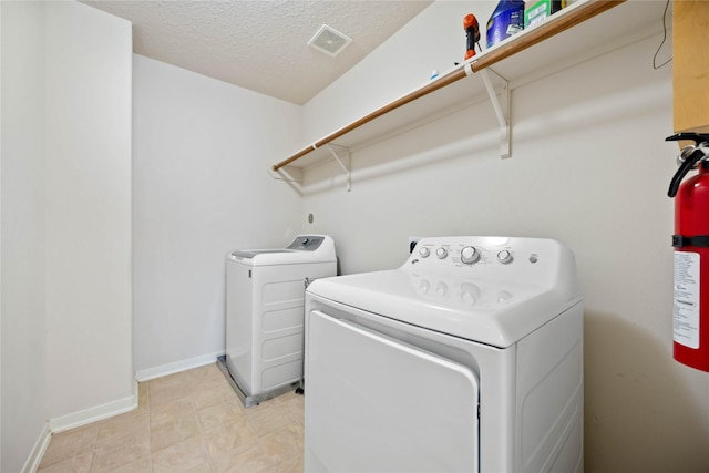 laundry area with washer and dryer and a textured ceiling