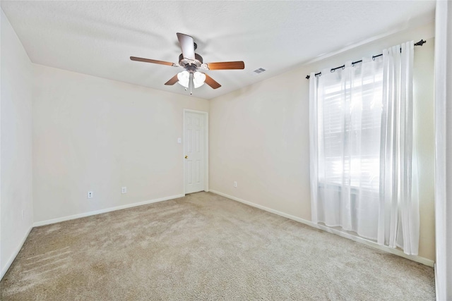 unfurnished room with a textured ceiling, ceiling fan, and light carpet