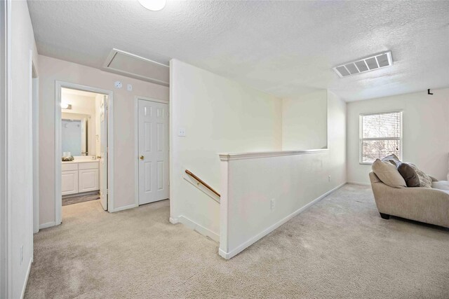 hall featuring light carpet and a textured ceiling