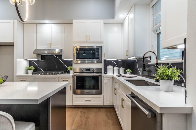 kitchen with white cabinets, decorative backsplash, stainless steel appliances, and sink