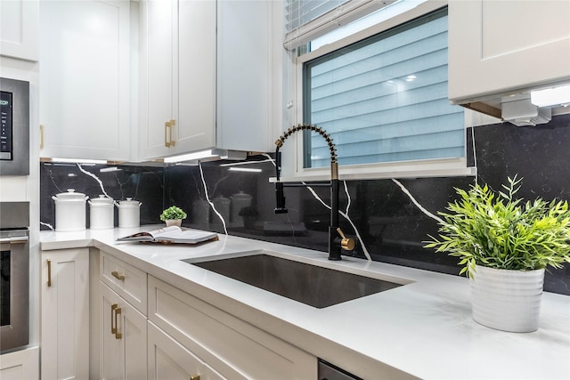 kitchen with white cabinets, sink, backsplash, and stainless steel appliances