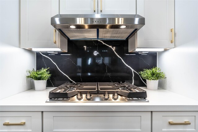 room details with white cabinets, decorative backsplash, stainless steel gas cooktop, and range hood