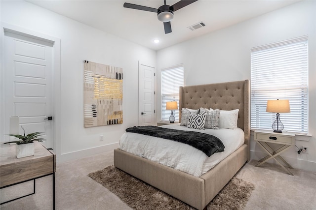 bedroom with light colored carpet, multiple windows, and ceiling fan