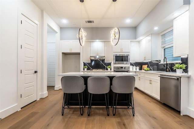 kitchen with a center island, stainless steel appliances, light hardwood / wood-style flooring, and hanging light fixtures