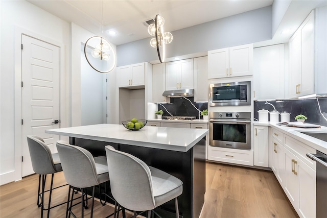 kitchen with tasteful backsplash, a center island, hanging light fixtures, and appliances with stainless steel finishes