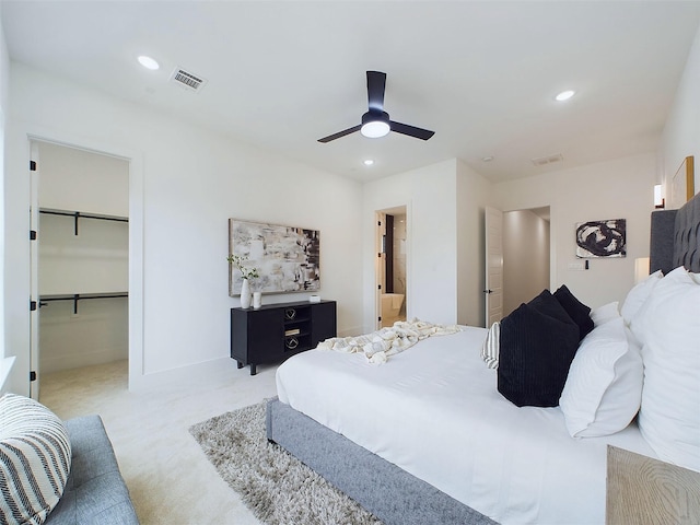 bedroom with light carpet, ensuite bathroom, ceiling fan, a spacious closet, and a closet