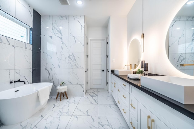 bathroom with vanity, a tub, and tile walls