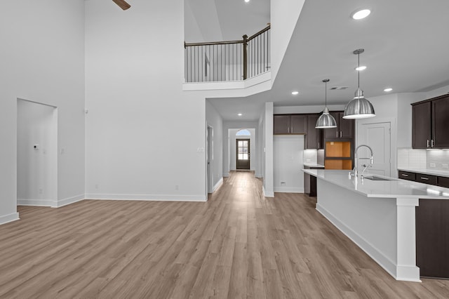 8327 Oceanmist Cove Dr, Cypress, TX 77433 - unfurnished living room with a sink, light wood finished floors, recessed lighting, a towering ceiling, and baseboards
