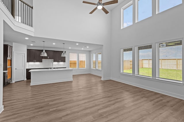 8327 Oceanmist Cove Dr, Cypress, TX 77433 - unfurnished living room featuring a high ceiling, ceiling fan, a sink, light wood-style floors, and plenty of natural light