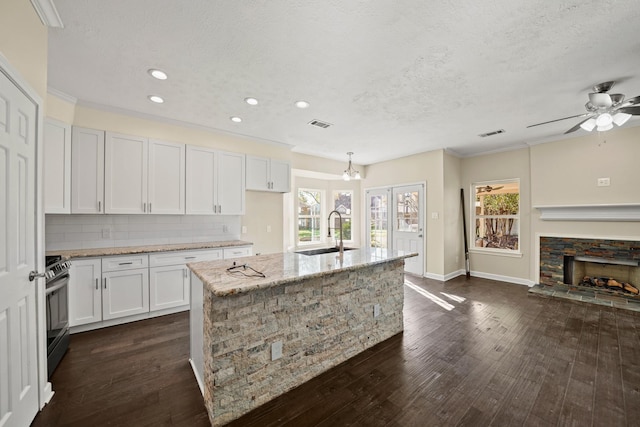 kitchen with sink, white cabinets, a center island with sink, and stainless steel range with electric cooktop