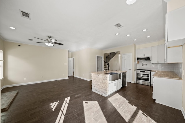 kitchen featuring white cabinetry, dark hardwood / wood-style flooring, a center island with sink, and appliances with stainless steel finishes