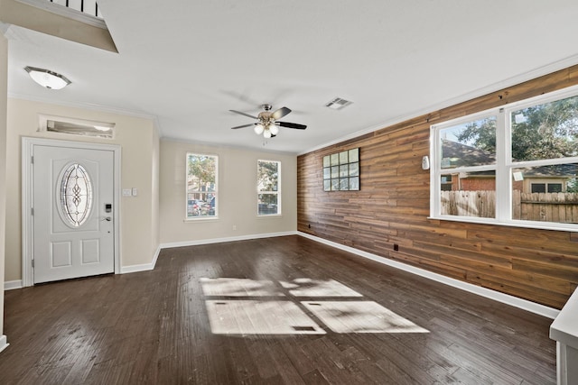 foyer with dark hardwood / wood-style flooring, ceiling fan, ornamental molding, and wood walls