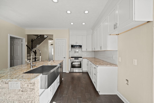 kitchen with light stone counters, dark wood-type flooring, sink, stainless steel range oven, and white cabinets