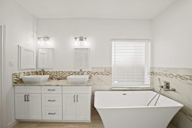 bathroom with a bathtub, vanity, and tile walls