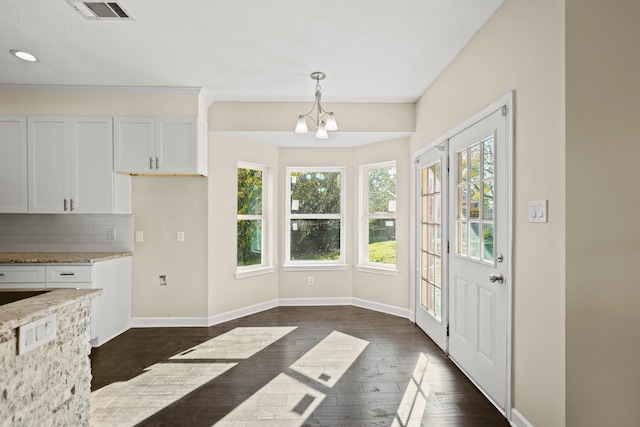 kitchen featuring light stone countertops, dark wood-type flooring, a chandelier, pendant lighting, and white cabinets