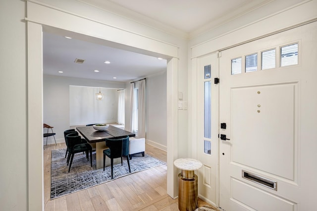 entryway with light hardwood / wood-style floors and ornamental molding