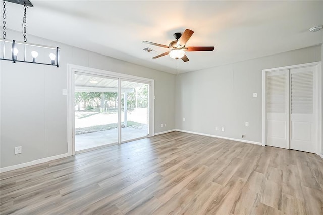 interior space with ceiling fan with notable chandelier and light hardwood / wood-style floors