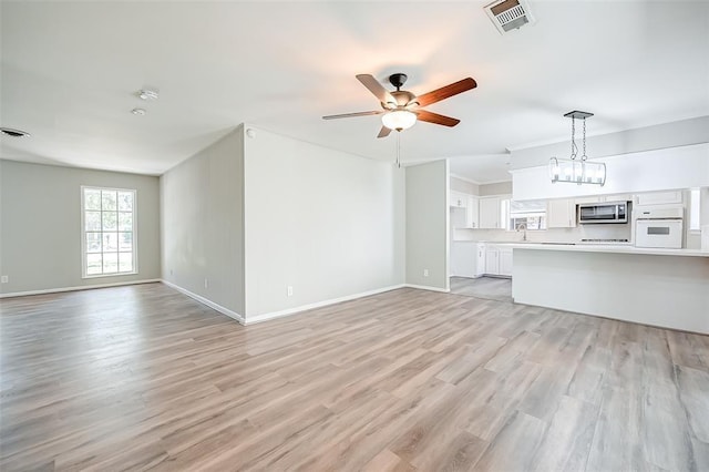 unfurnished living room featuring ceiling fan with notable chandelier, sink, and light hardwood / wood-style flooring