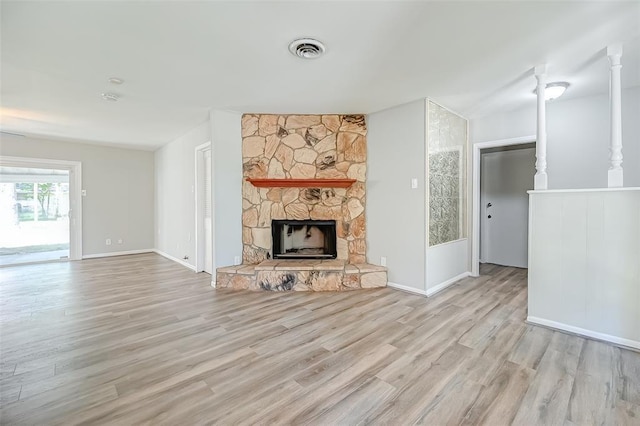 unfurnished living room with light hardwood / wood-style flooring and a stone fireplace