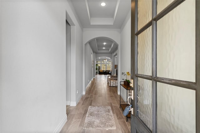 hall with a raised ceiling and wood-type flooring