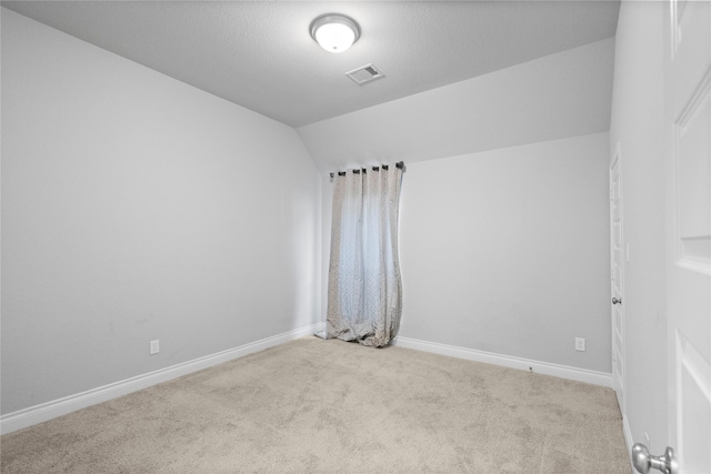 unfurnished room featuring light carpet and vaulted ceiling