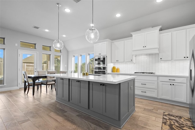 kitchen with a center island with sink, decorative light fixtures, white cabinets, and hardwood / wood-style flooring