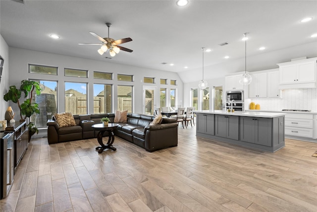 living room featuring light hardwood / wood-style floors, vaulted ceiling, ceiling fan, and sink