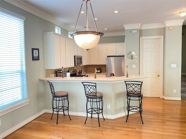 kitchen with a breakfast bar, kitchen peninsula, stainless steel appliances, and a wealth of natural light