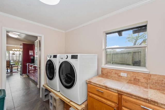 washroom with washer and dryer, a chandelier, dark tile patterned flooring, and ornamental molding