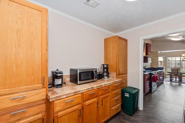 kitchen featuring dark tile patterned floors, ornamental molding, and appliances with stainless steel finishes