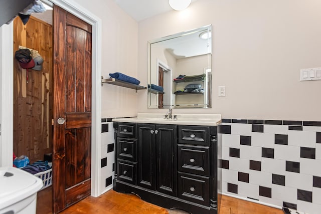 bathroom featuring vanity, wood-type flooring, and tile walls