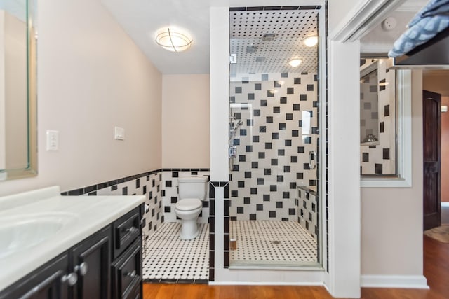 bathroom with hardwood / wood-style floors, vanity, a shower with shower door, and tile walls