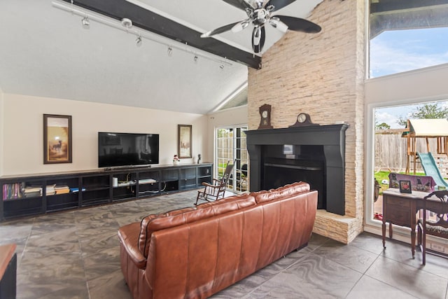 tiled living room with a fireplace, high vaulted ceiling, and plenty of natural light