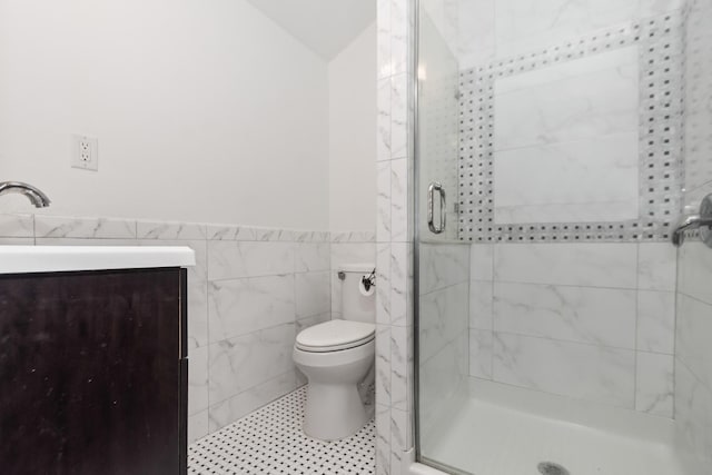 bathroom featuring sink, a shower with door, tile walls, and toilet