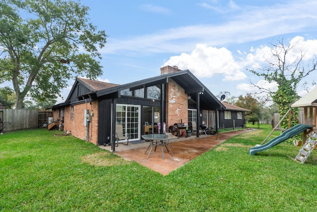 rear view of house featuring a lawn, a playground, and a patio