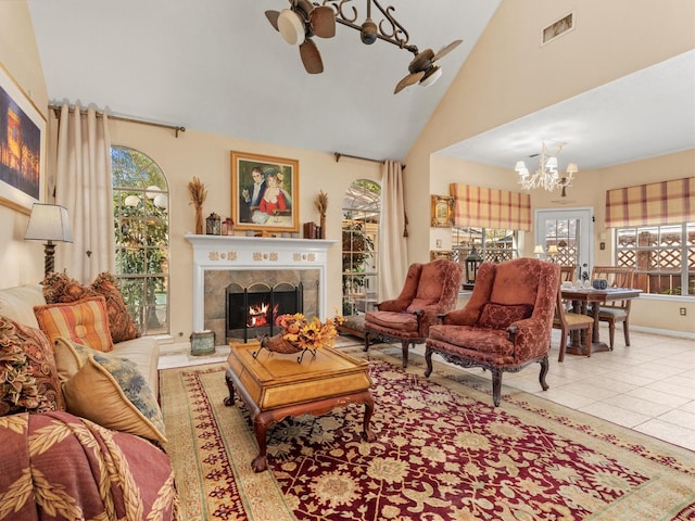 living room featuring a tile fireplace, ceiling fan with notable chandelier, a healthy amount of sunlight, and light tile patterned flooring